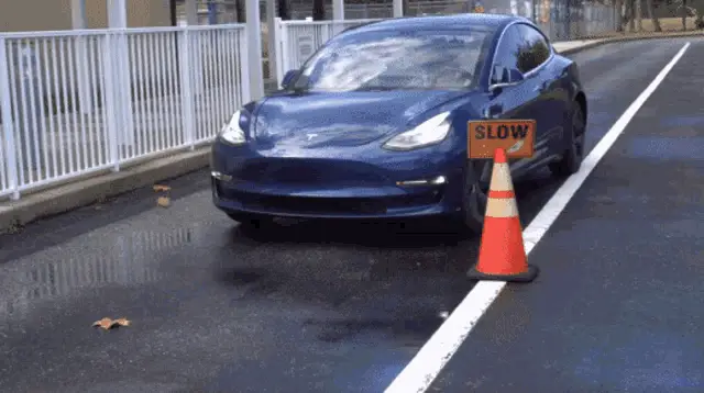 Blue Tesla Model 3 Drives Past Slow Sign