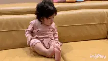 Cute Baby Girl Playfully Falls on Couch