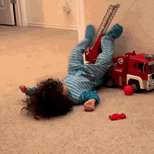 Pouting Manu Next to Toy Fire Truck