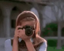 Cher from Clueless taking a picture and smiling